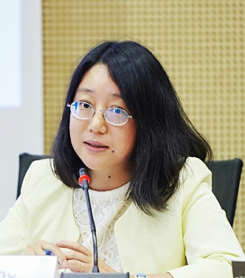 Woman with glasses speaking on a microphone